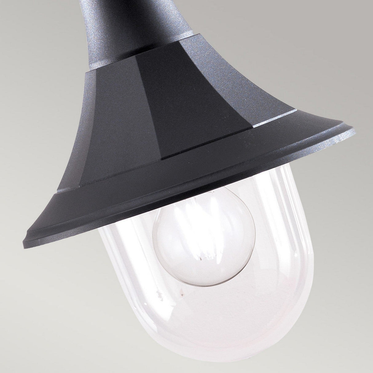 The Shannon 1 Light Outdoor Chain Pendant showcases a black corrosion-proof polymer lamp fixture paired with a clear glass cover, revealing a visible light bulb inside. This pendant features a cone-shaped top and an IP44 rating, all set against a plain gray background.