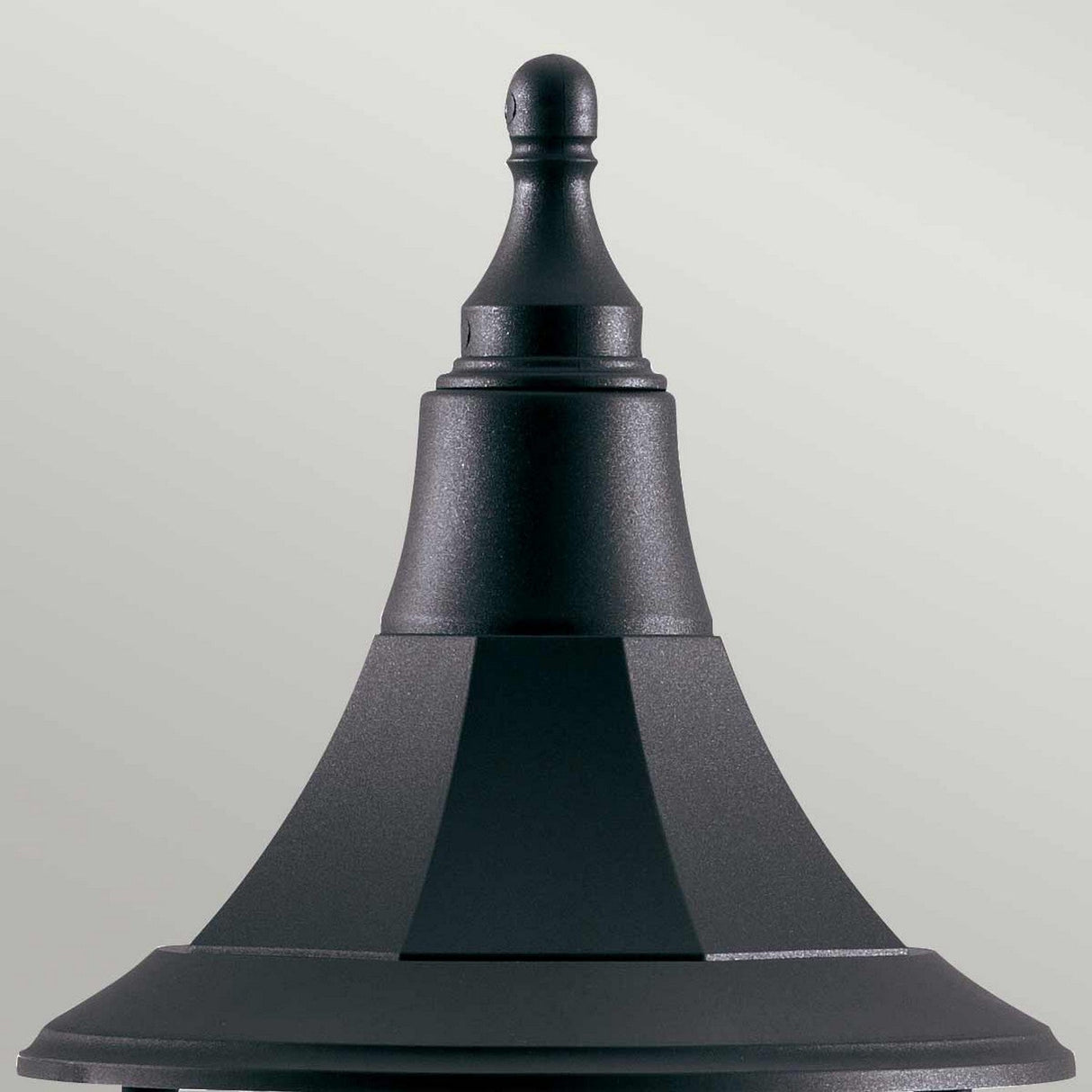Close-up of the Shannon 1 Light Pedestal - Black against a light gray background. This fixture, with its IP44 rating and corrosion-proof construction, showcases a pointed finial on top and a tapered, tiered design that lends it an elegant and classic look.