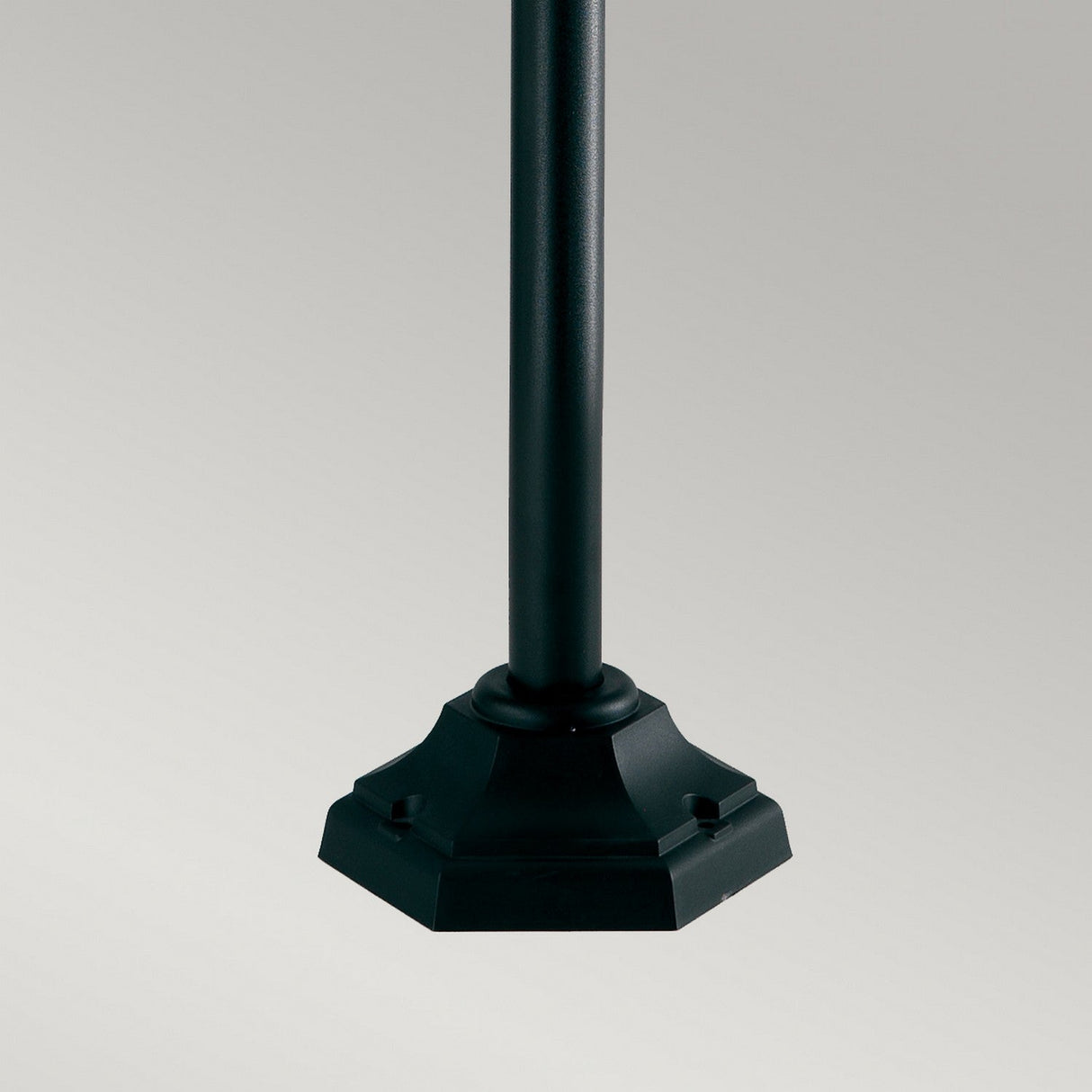 Introducing the Shannon 1 Light Pillar - Black, a sleek metal pole with a decorative hexagonal base, perfect for outdoor lighting applications. Set against a plain gray background, this pillar boasts a smooth, corrosion-proof finish and features subtle detailing around its weather-resistant base.