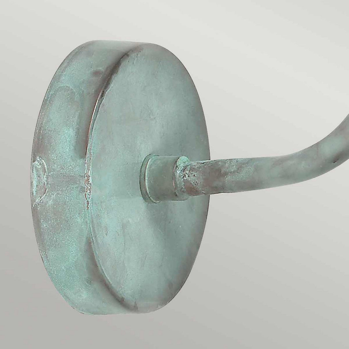 Close-up of the Sheldon 1 Light Outdoor Wall Light in verdigris, showcasing its weathered round metal knob attached to a curved handle against a light gray background.