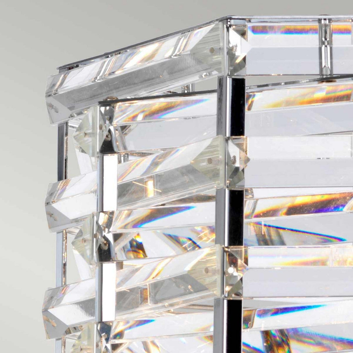 A close-up reveals an abstract design with clear, angular glass strips arranged vertically and horizontally, secured by polished nickel accents. Light reflects off the glass in a contemporary manner, producing subtle rainbow effects reminiscent of the Shoal 1 Light Pendant - Polished Nickel.