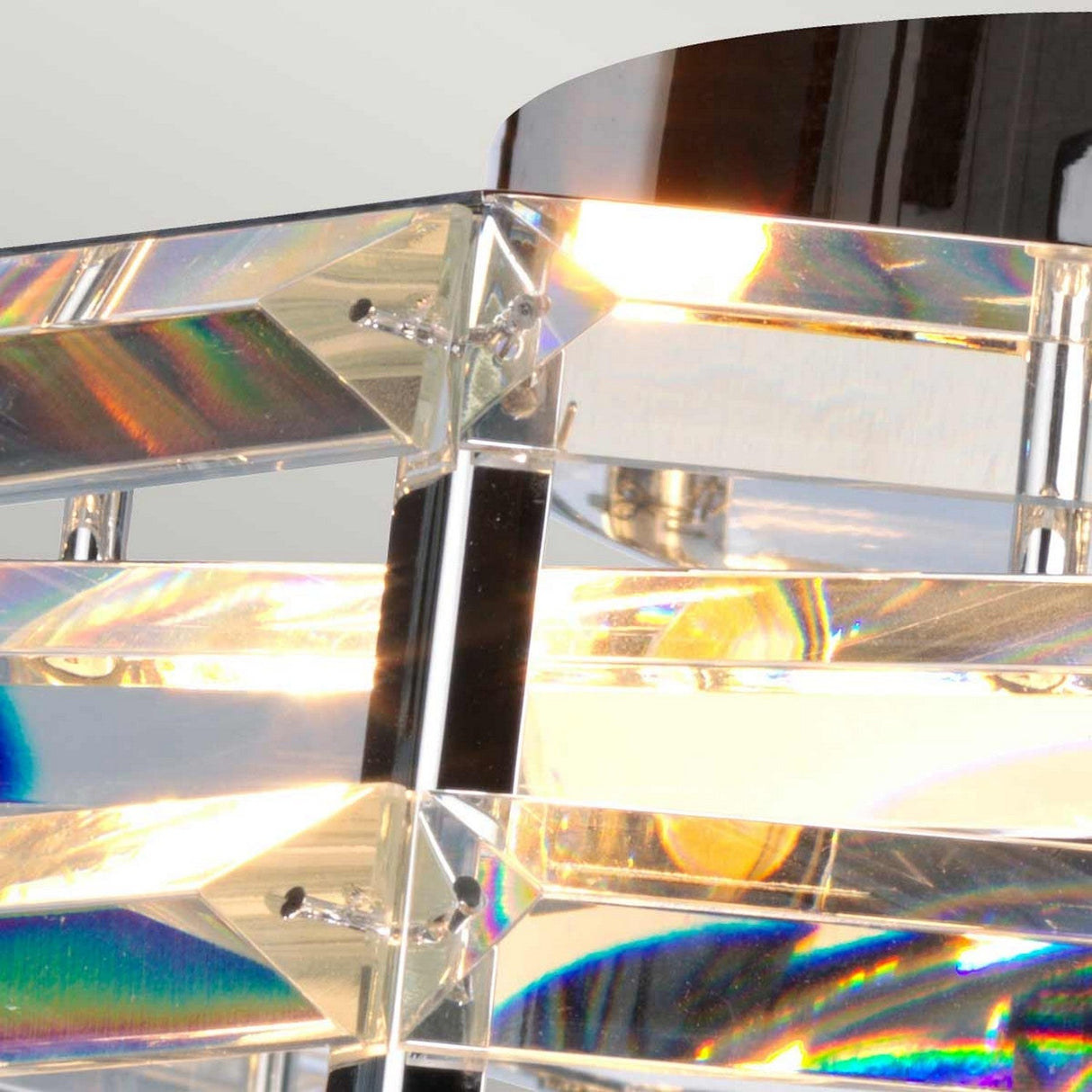 A close-up of the Shoal 4 Light Flush - Polished Nickel fixture showcases its multiple reflective panels that create vibrant rainbow colors. The layered arrangement of intertwining crystals casts a warm glow, highlighting the elegant polished nickel and glass design.