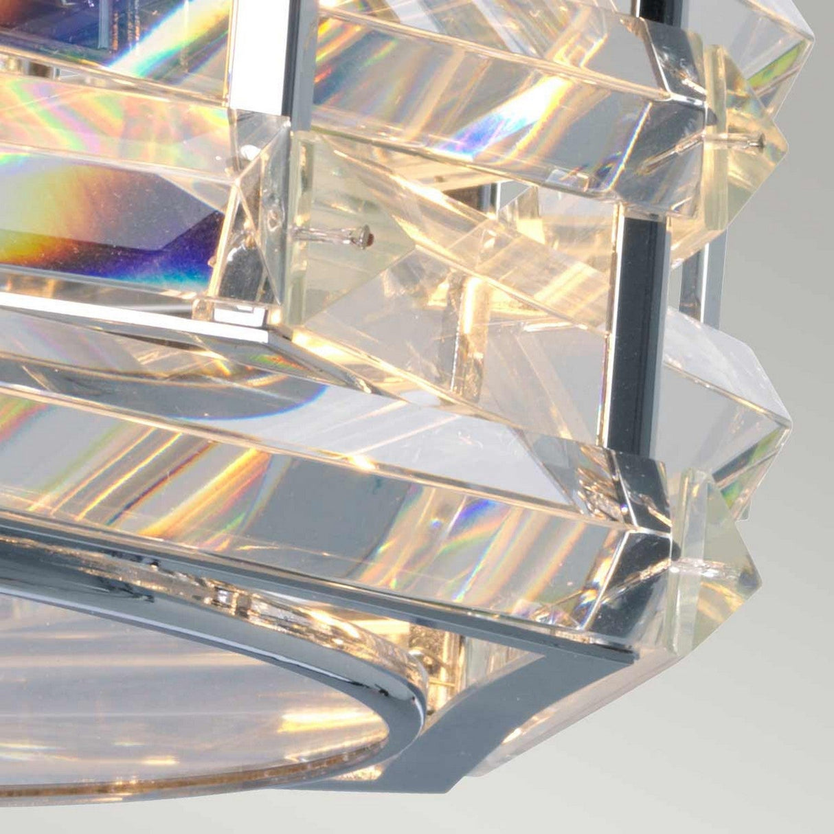 A detailed view of a faceted, geometric crystal structure reflecting vibrant light. Intertwined crystals form rainbow-like patterns on the transparent surface, surrounded by polished nickel edges, reminiscent of the Shoal 4 Light Flush - Polished Nickel.