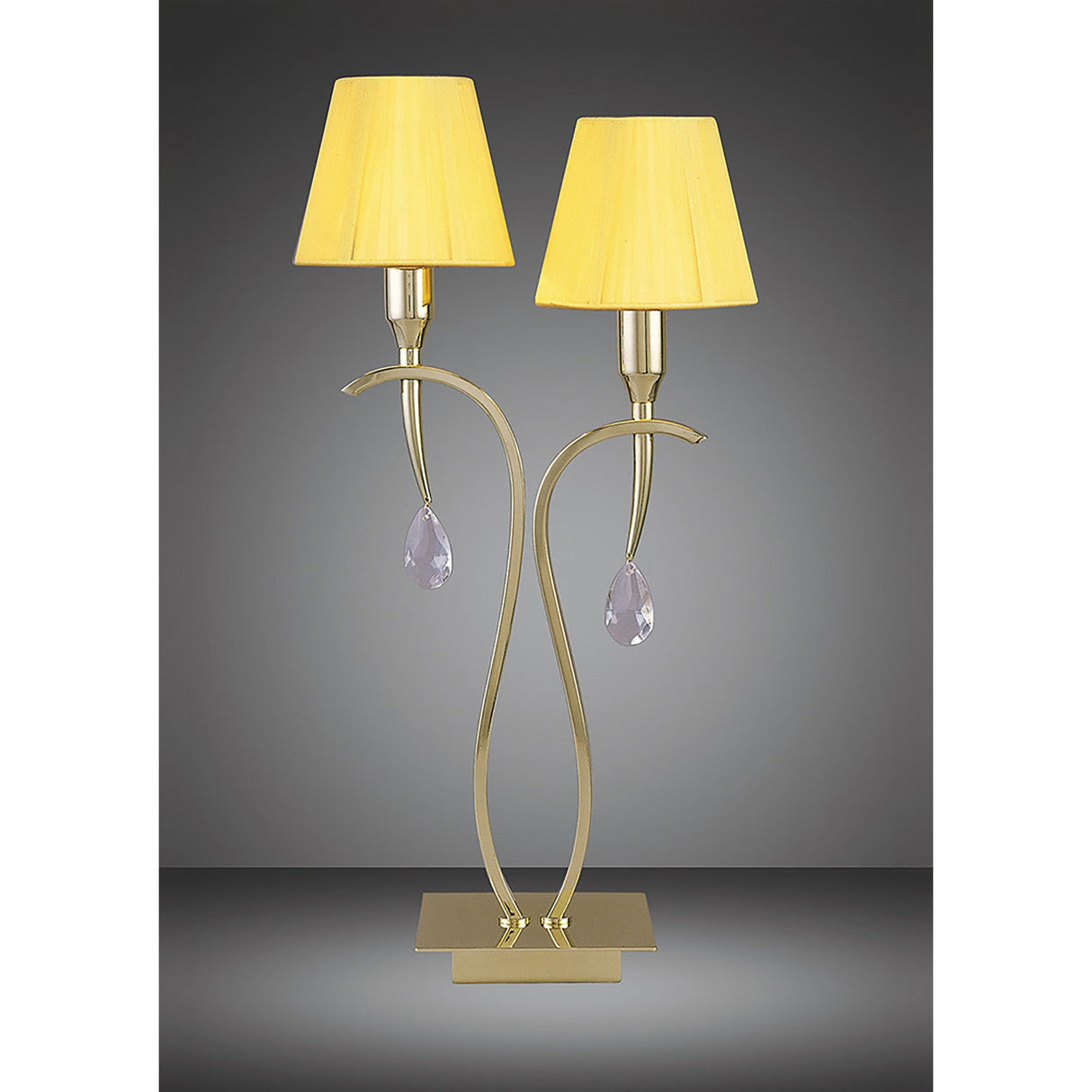 The Siena 2 Light Crystal Table Lamp features curved brass stems with amber shades and crystal drop ornaments on a rectangular gold base, offering stylish ambient lighting against a gray backdrop.