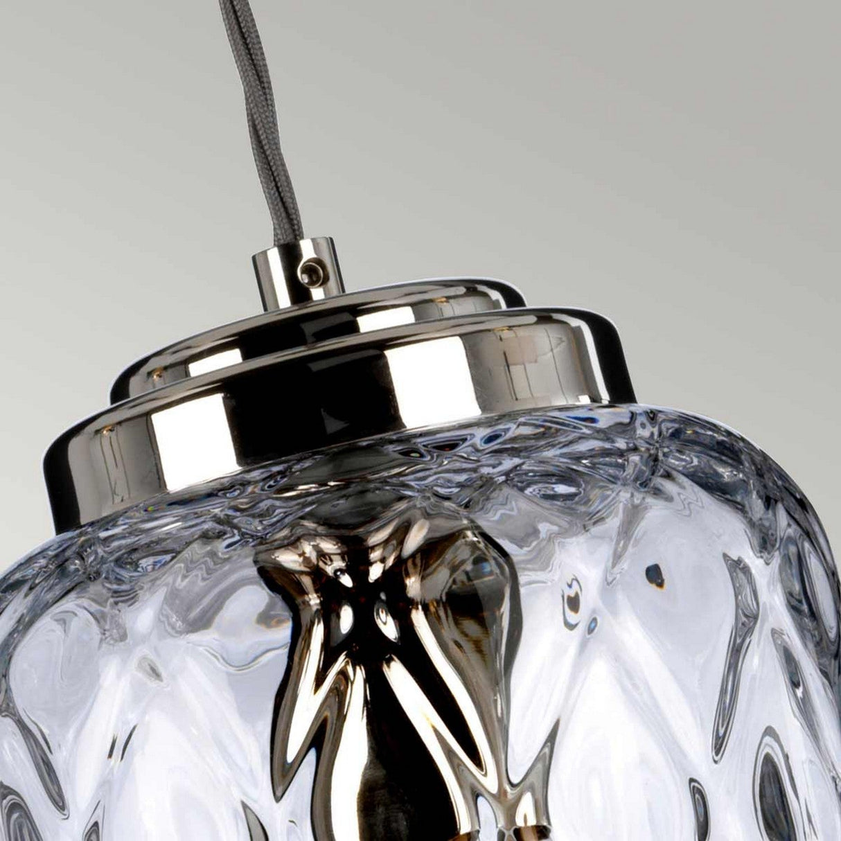 Close-up of the Sola 1 Light Pendant, showcasing its transparent, textured clear glass shade and polished nickel top, suspended by a cable against a neutral background.