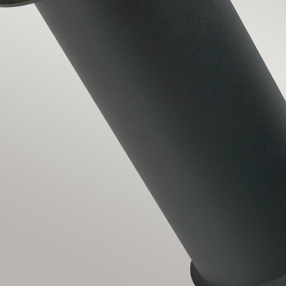 Close-up of the Stockholm 1 Light Medium Bollard in its sleek, black cylindrical form with a slightly matte finish, set against a light gray background. This Scandinavian design piece appears to be made of metal or plastic, its smooth surface exuding elegance akin to an outdoor lighting fixture.