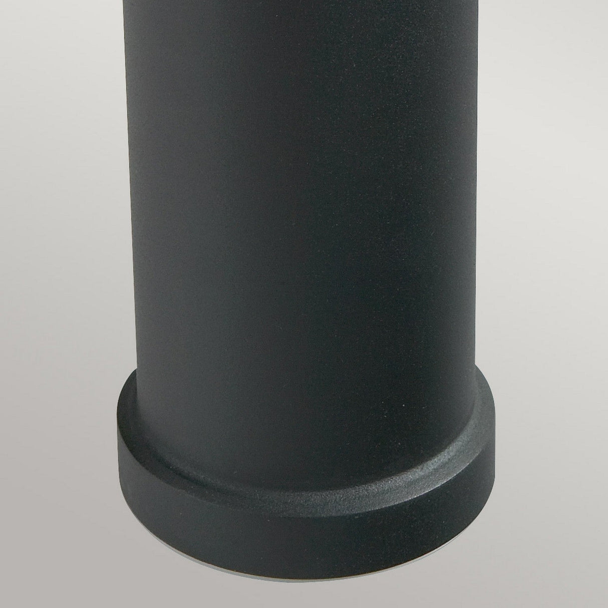 Close-up of the base of the Stockholm 1 Light Medium Bollard - Black, set against a gray background. The smooth, matte surface is reminiscent of Scandinavian design.