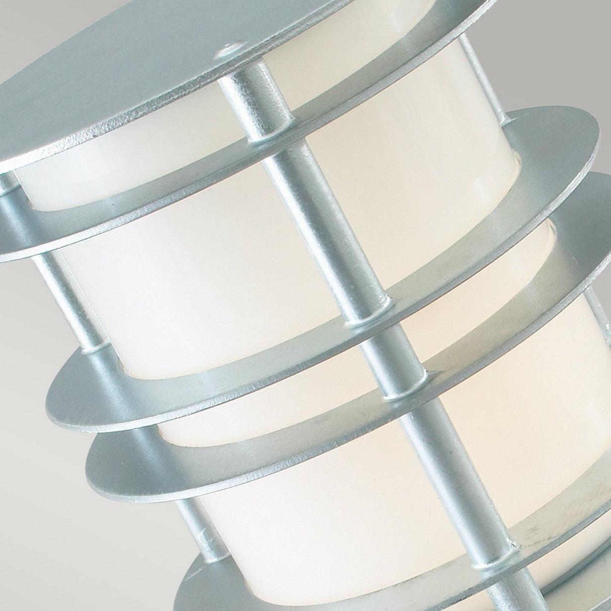 Close-up of the Stockholm Medium Bollard - Silver, featuring a modern outdoor lighting fixture with cylindrical layers. The lamp showcases three stacked, round, frosted glass sections separated by galvanized steel rings, offering a sleek and contemporary design with an IP65 rating.