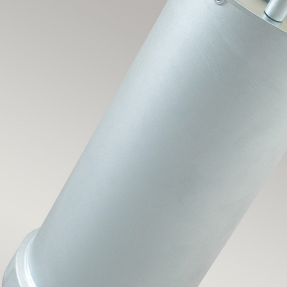 Close-up of the Stockholm Medium Bollard - Silver, a sleek cylindrical object made from galvanized steel with a smooth finish and a slightly textured bottom edge. Designed for outdoor lighting, it features an IP65 rating set against a gradient of light gray in the background.