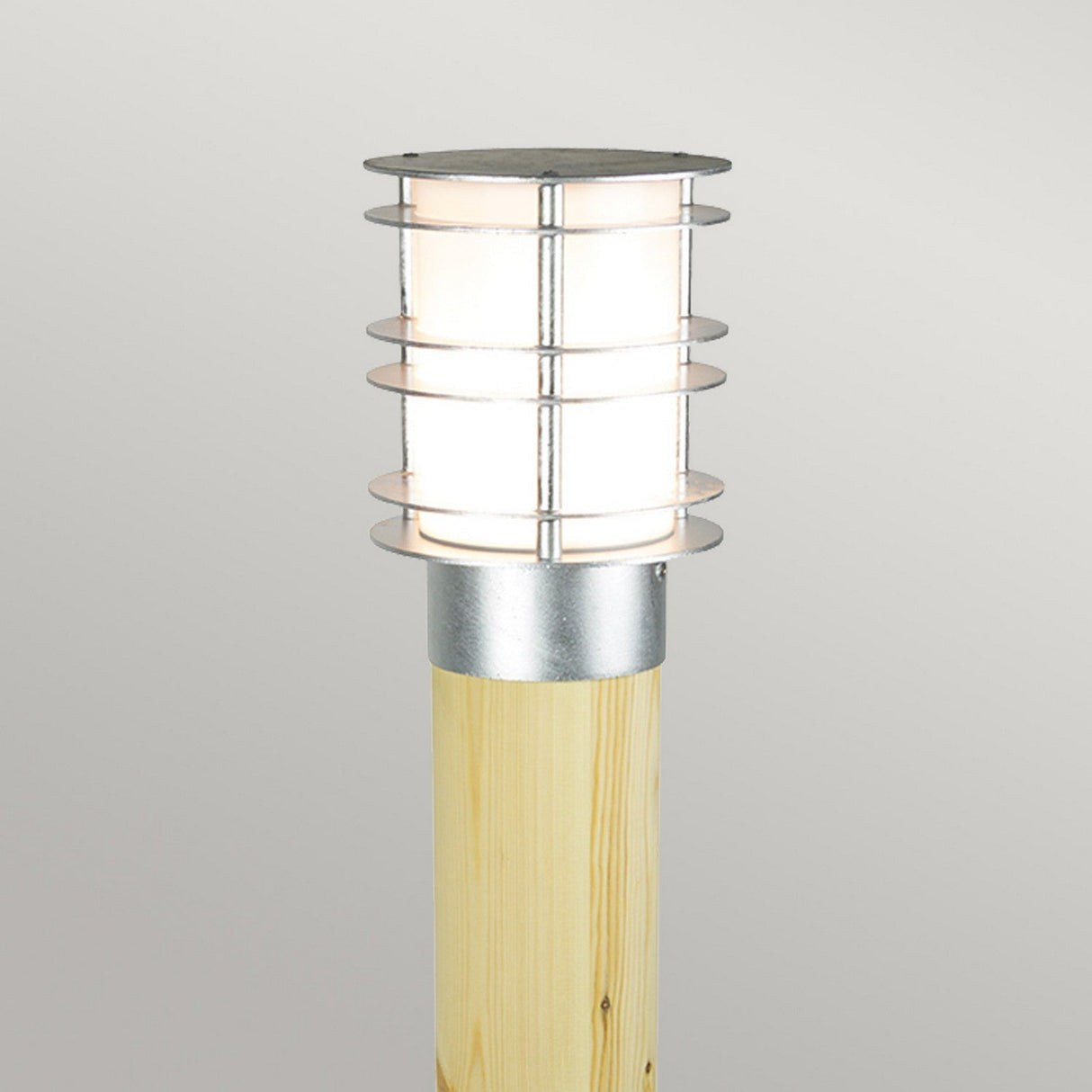 Introducing the Stockholm Large Bollard in Natural Wood and Silver, a contemporary outdoor lamp with a natural wood design and a cylindrical metal shade. This sleek lamp features galvanized steel rings encircling the light source, set against a neutral background. It's IP65 rated to ensure superior durability across diverse weather conditions.