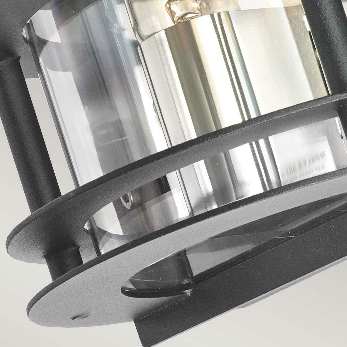 Close-up of the Stockholm Outdoor 1 Light Flush Light, showcasing its modern design with a black frame and clear glass cover. The fixture's combination of dark and transparent elements highlights a contemporary aesthetic against a light background.