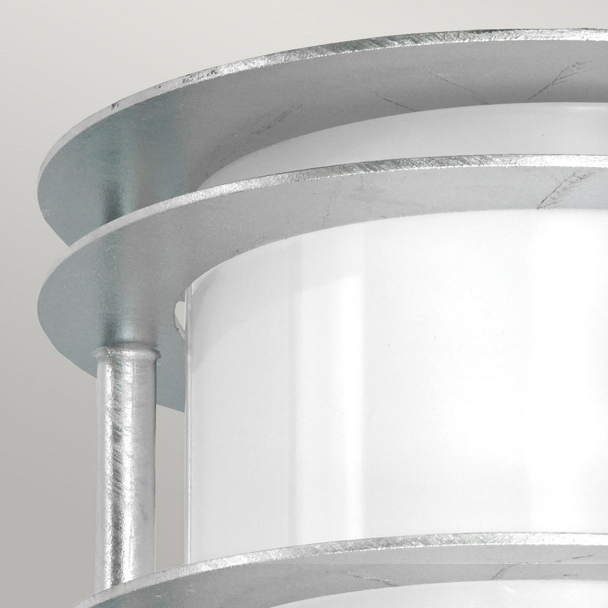 Close-up of a contemporary, cylindrical metallic structure with a white central body and silver circular layers resembling the Stockholm Outdoor 1 Light Flush Light - Silver With Opal Glass. The design showcases sleek lines and a minimalist aesthetic.