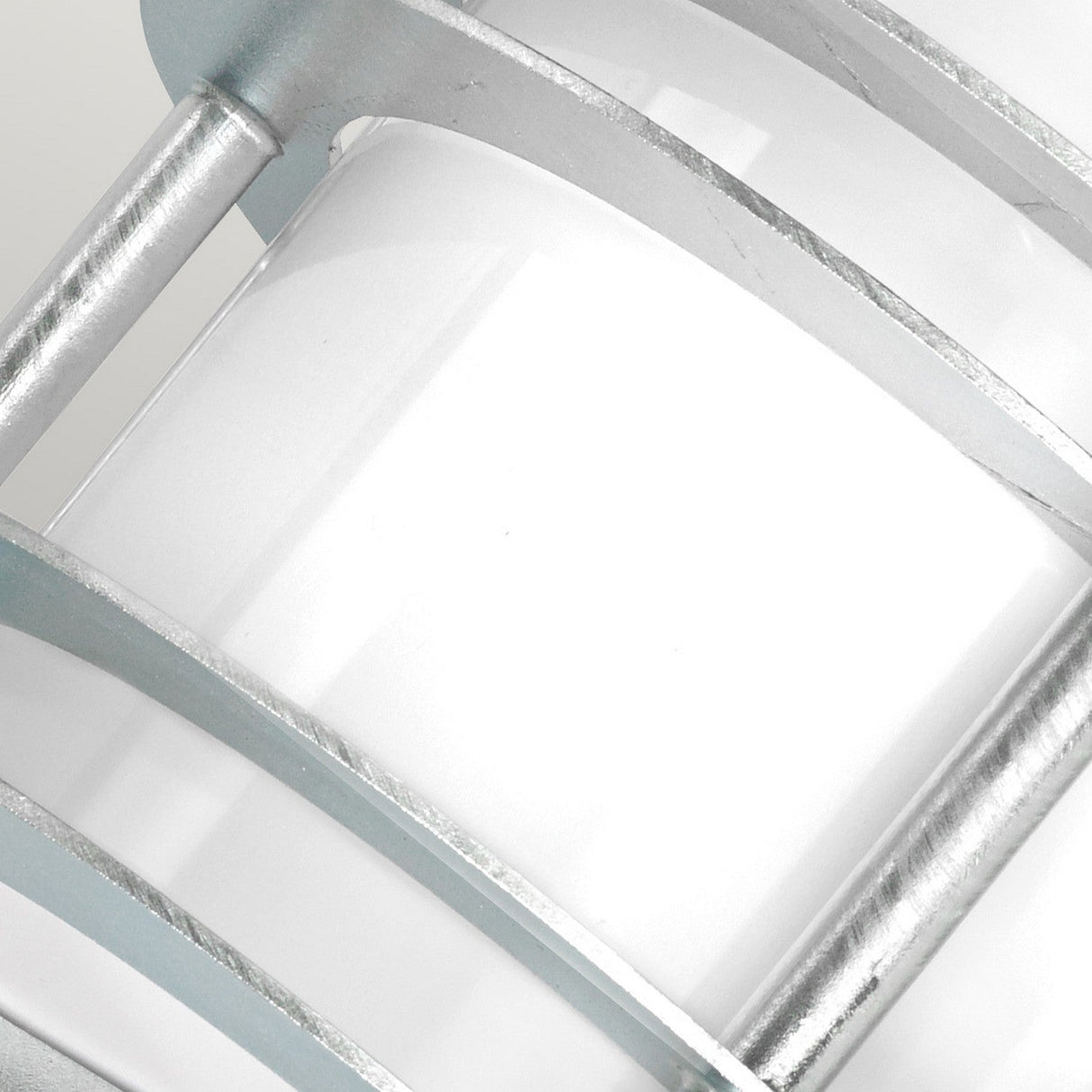 A close-up of the Stockholm Outdoor 1 Light Flush Light showcases its modern cylindrical design with an opal glass shade and silver metal accents, offering a sleek, industrial appearance.