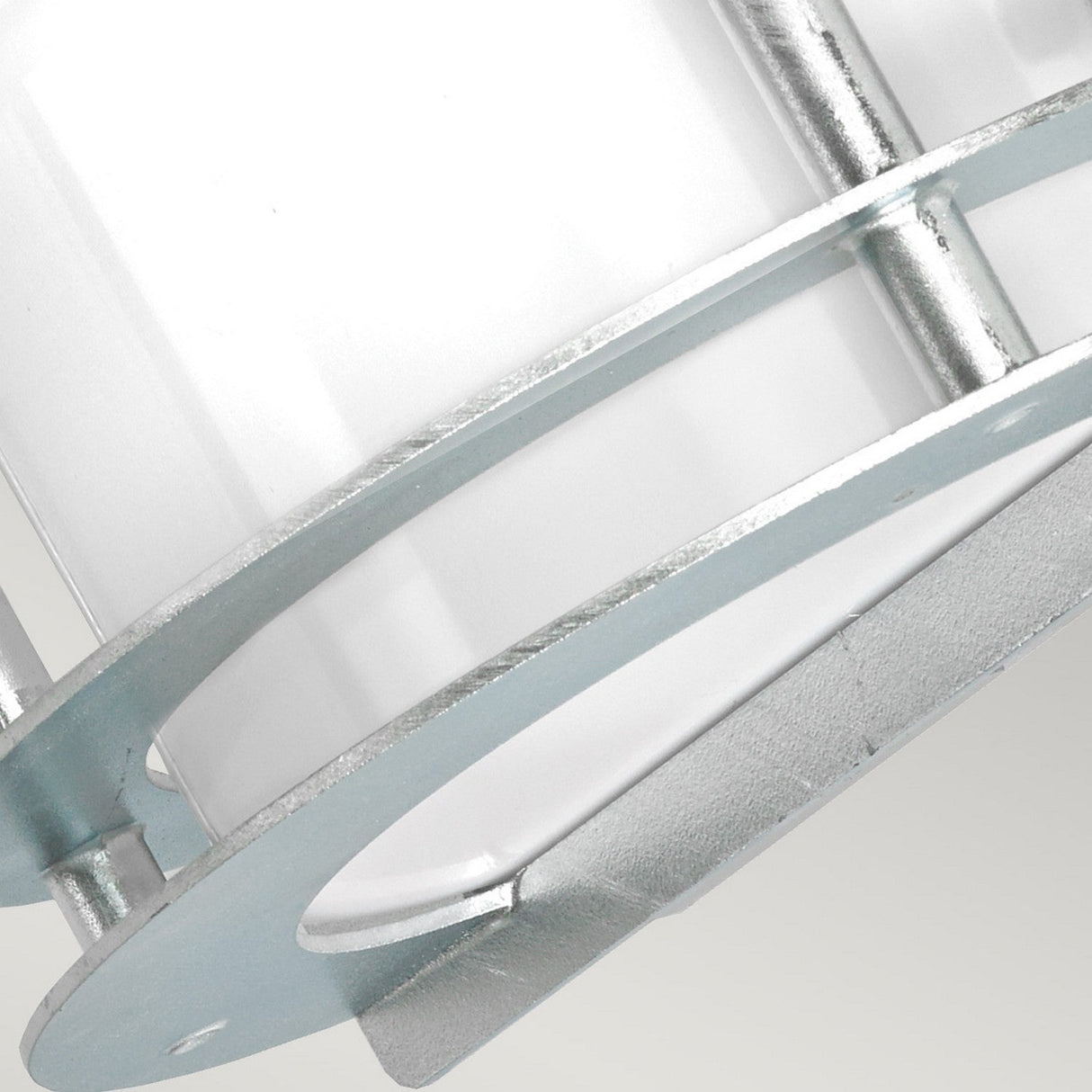 A close-up showcases a metallic, cylindrical cage-like structure surrounding an opal glass object, reminiscent of the sleek design of the Stockholm Outdoor 1 Light Flush Light - Silver With Opal Glass. The shiny finish, featuring horizontal and vertical bars, stands out against a soft gradient gray background.