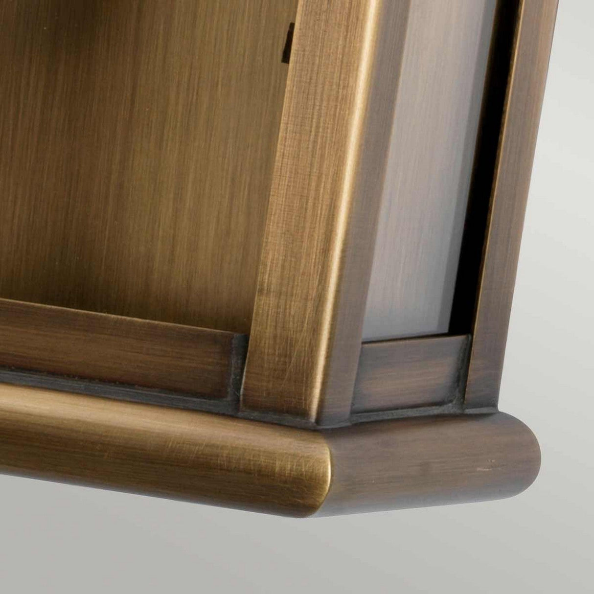 Close-up of the aged brass, angular frame with a brushed texture. The St Martins 1 Light Outdoor Wall Light showcases clean lines and a subtle sheen, highlighting its hand-crafted edges. The background is slightly blurred to emphasize the details of the frame.