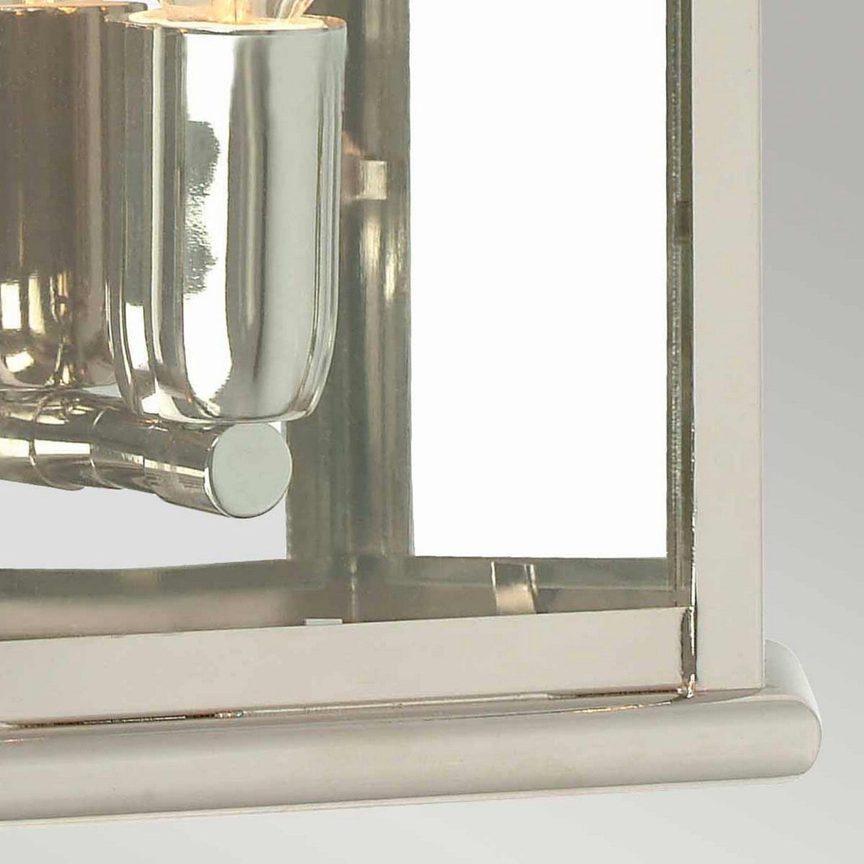 A close-up of the St Martins 1 Light Outdoor Wall Light showcases its modern design, featuring a polished nickel finish and glass panels. The reflective surface enhances light, emphasizing its sleek, minimalist aesthetic against a soft, neutral gradient background.