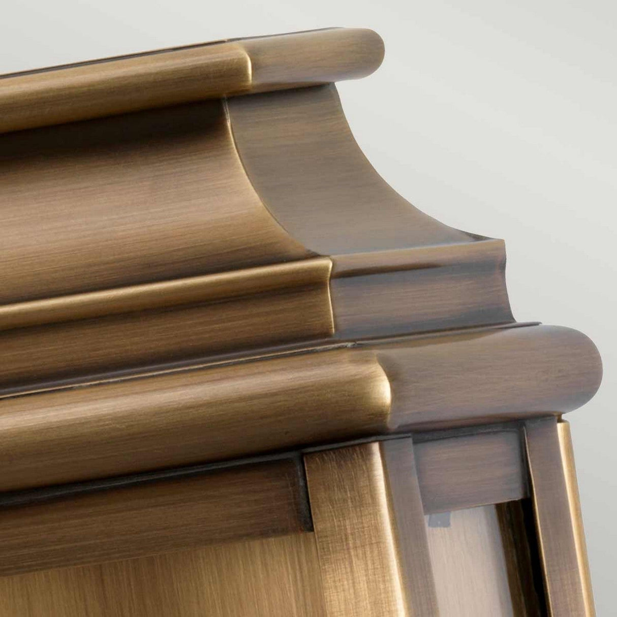 Close-up of a St Pauls 1 Light Outdoor Wall Light featuring an aged brass finish. The image highlights the craftsmanship and detail, resembling that of finely polished wooden furniture with a warm, golden brown hue.