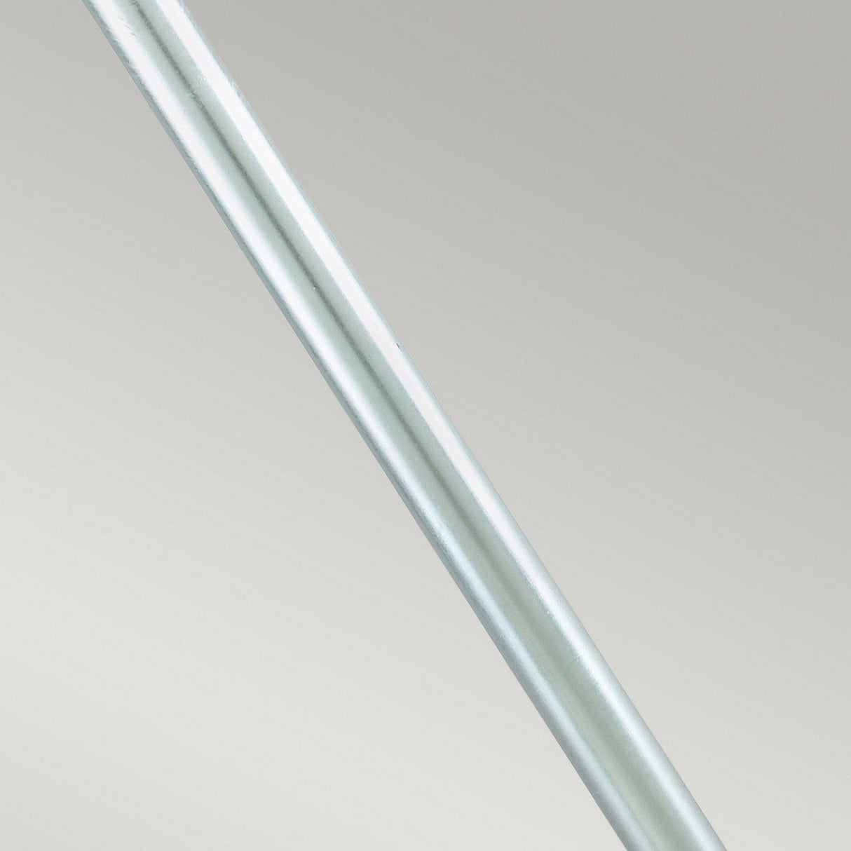 Capturing the essence of Scandinavian design, a detailed view of the Stockholm 1 Light Pillar - Silver showcases its sleek, metallic form, positioned diagonally against a simple gray backdrop. The galvanized steel surface is smooth and reflective, creating gentle highlights along its length.