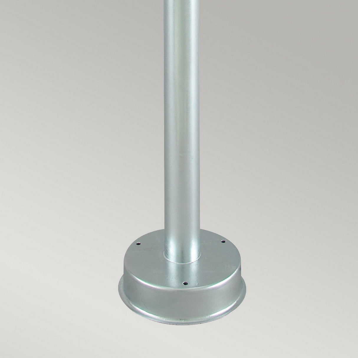 The image features the Stockholm 1 Light Pillar - Silver, showcasing a close-up of its galvanized steel structure and circular base against a plain, light gray background. Reminiscent of Scandinavian design, the sturdy pillar is securely mounted onto the base with several visible screws around the bottom.