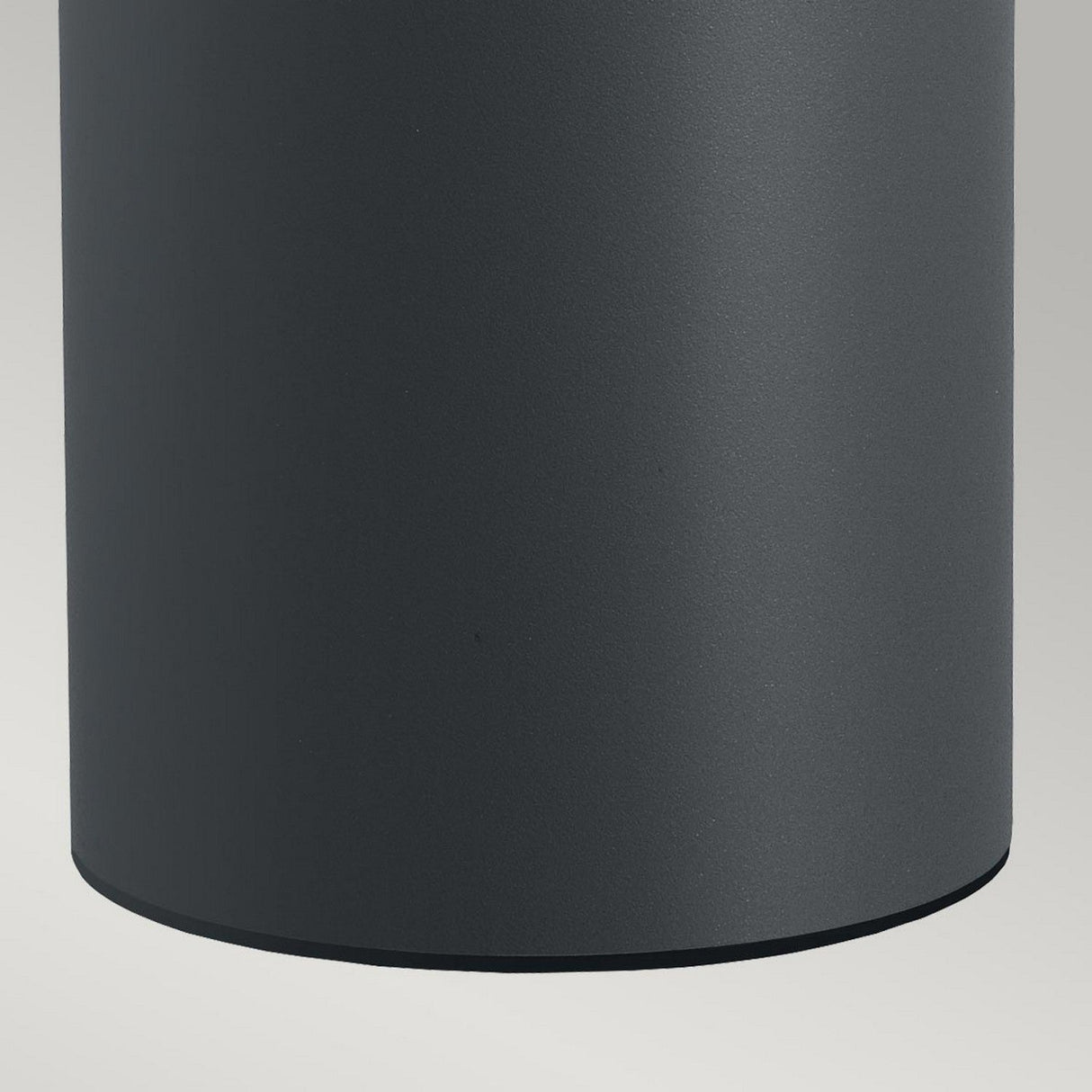 A close-up view of the Stavanger LED Medium Bollard in a graphite matte finish set against a light gray background. The smooth surface of this weather-resistant cylinder curves down to an invisible base, ensuring durability and style in any setting.