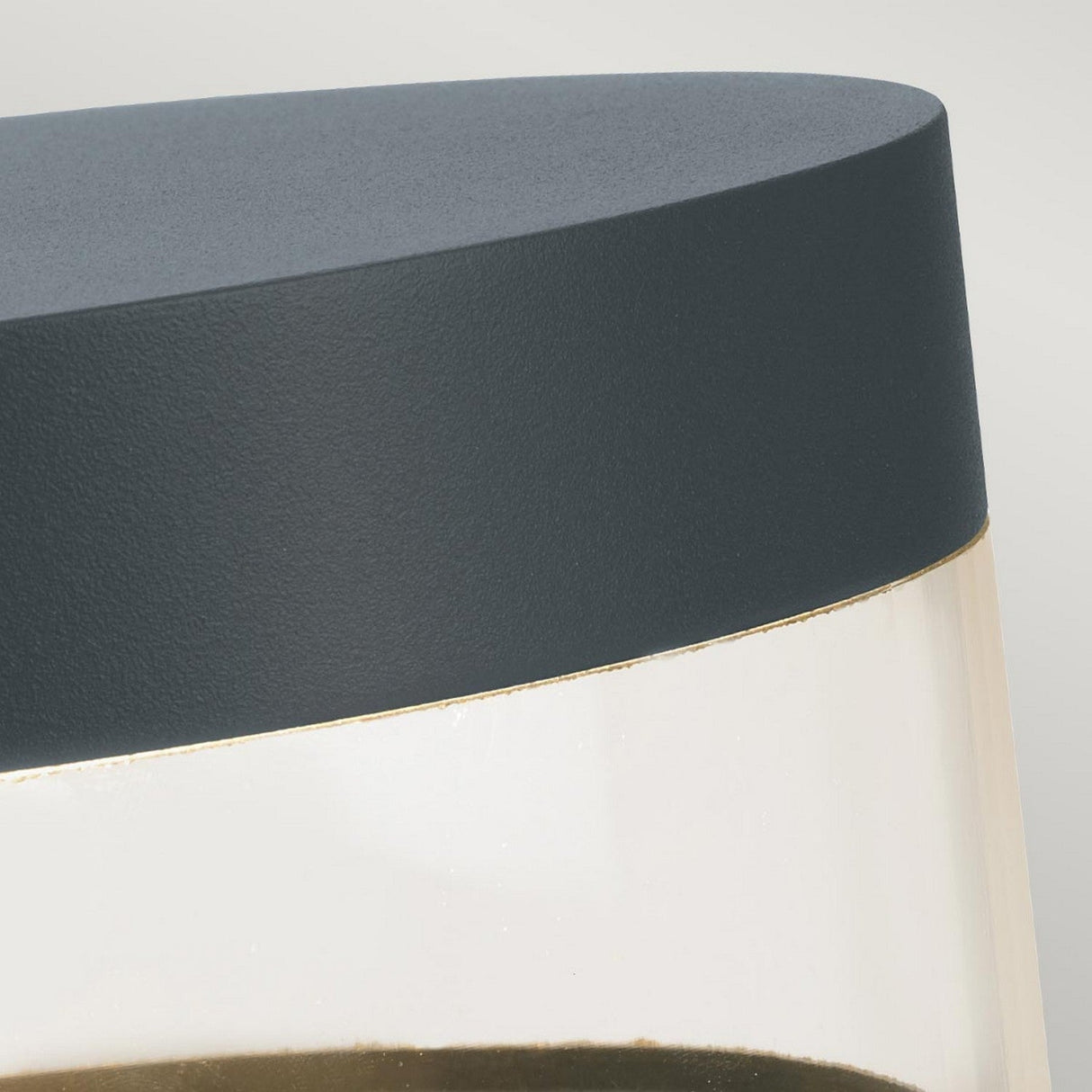 Close-up of the Stavanger LED Small Bollard in graphite, showcasing a container with a dark gray lid and clear body. The light gray background accentuates its sleek, minimalist design, reminiscent of contemporary LED bollard fixtures.