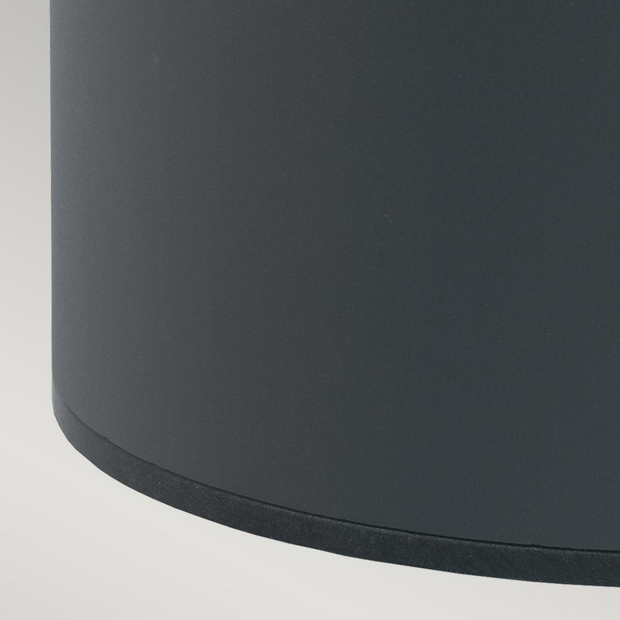 Close-up of the Stavanger LED Small Bollard in graphite finish, with a matte black cylindrical design set against a light gray background. The smooth surface casts a slight shadow on the right edge, reflecting an elegant solution perfect for outdoor lighting needs.
