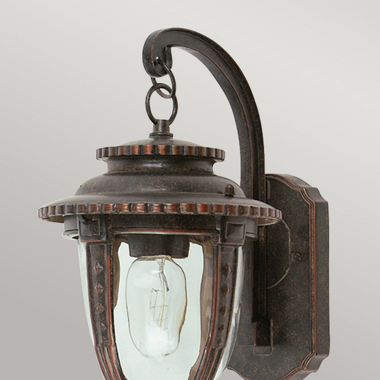 Introducing the St Louis 1 Light Outdoor Medium Wall Light in Weathered Bronze—a vintage-style fixture featuring a clear glass enclosure. It boasts a curved arm and decorative elements at the top and bottom, beautifully exposing the visible bulb inside.