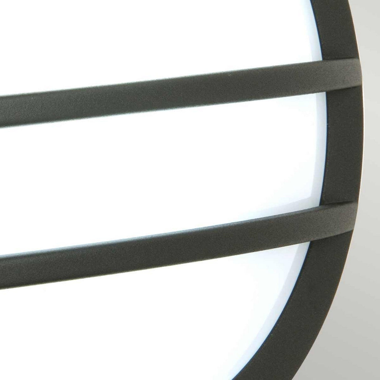 A close-up of the Sven 1 Light Outdoor Wall/Ceiling Light in Graphite showcases a round white surface featuring three horizontal black bars, capturing a modern aesthetic. Crafted from die-cast aluminum, this minimalist design contrasts beautifully against a plain light gray background.
