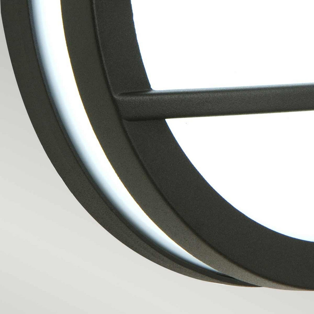 Close-up of the Sven 1 Light Outdoor Wall/Ceiling Light - Graphite, showcasing its contemporary circular design and sleek black frame crafted from die-cast aluminum. The light emits a bright white glow, enhancing its minimalist aesthetic against a plain background.