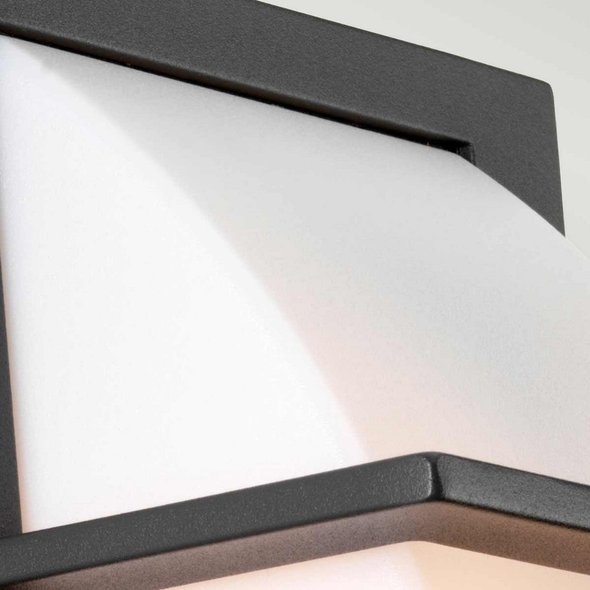 Close-up of the Sven 1 Light Outdoor Wall Light - Graphite, featuring a white, curved frosted glass shade encased in a sleek, graphite-colored rectangular black metal frame. The IP65-rated design emphasizes the smooth and minimalistic aesthetic of this modern fixture.