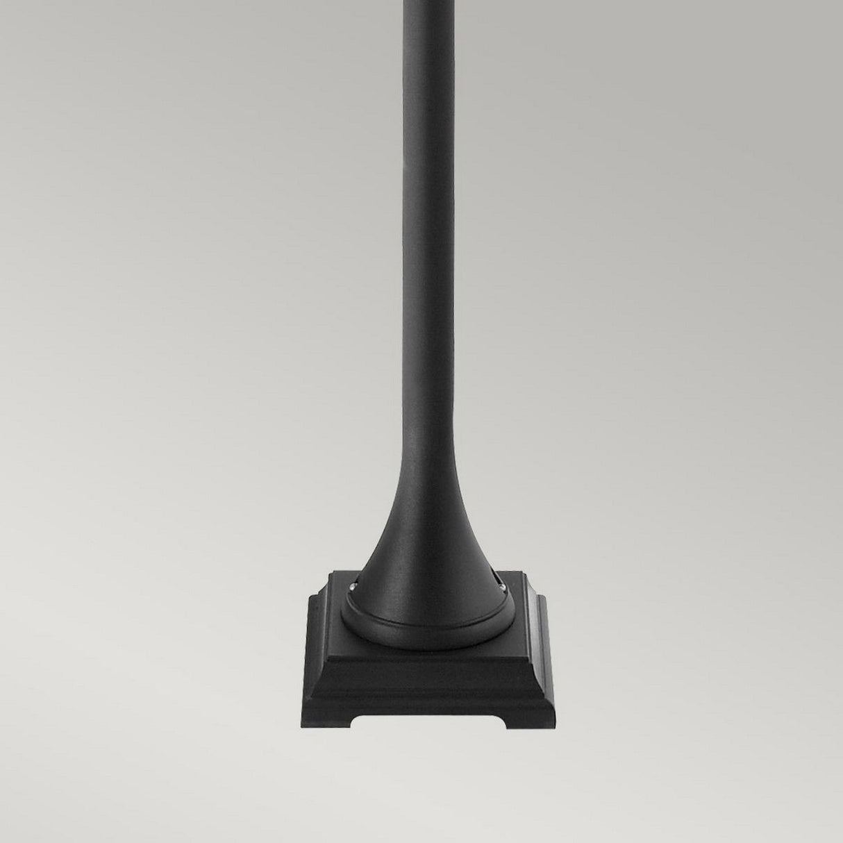The Turin 1 Light Pillar - Black, crafted from die-cast aluminum, stands elegantly against a plain gray background. Its black, cylindrical form slightly widens toward the decorative, angular base, seamlessly merging function and style into outdoor landscapes.