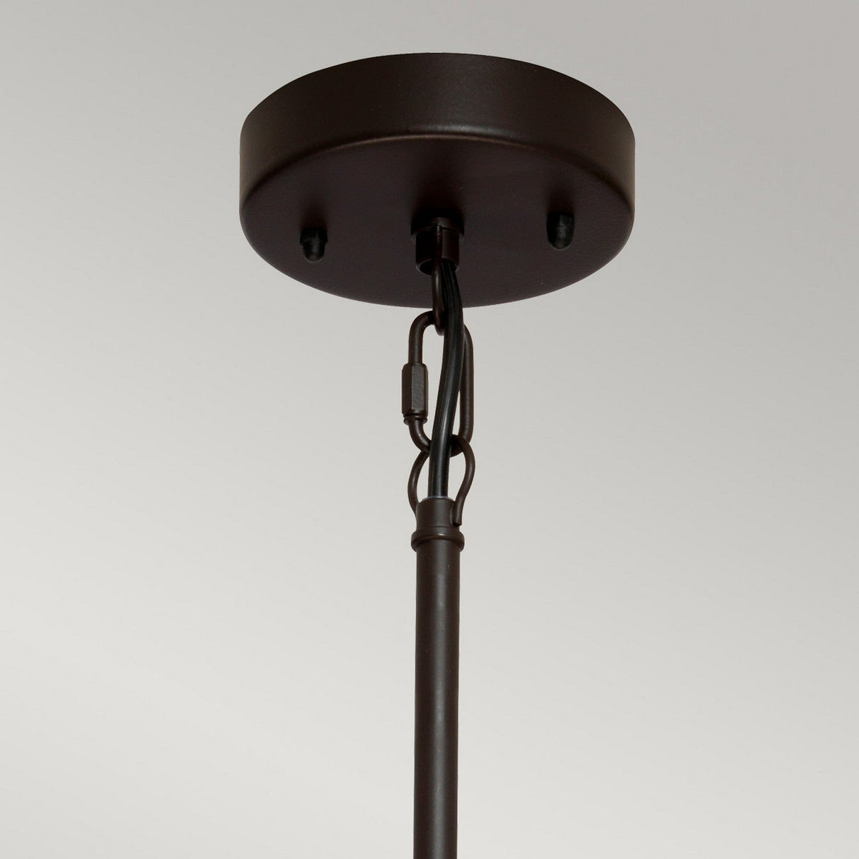 Close-up of the ceiling-mounted bracket for the Taiko 3 Light Chandelier - Olde Bronze, showcasing its circular base and cylindrical rod. The Olde Bronze finish enhances its sculptural appeal, with black wiring visibly connecting the rod.