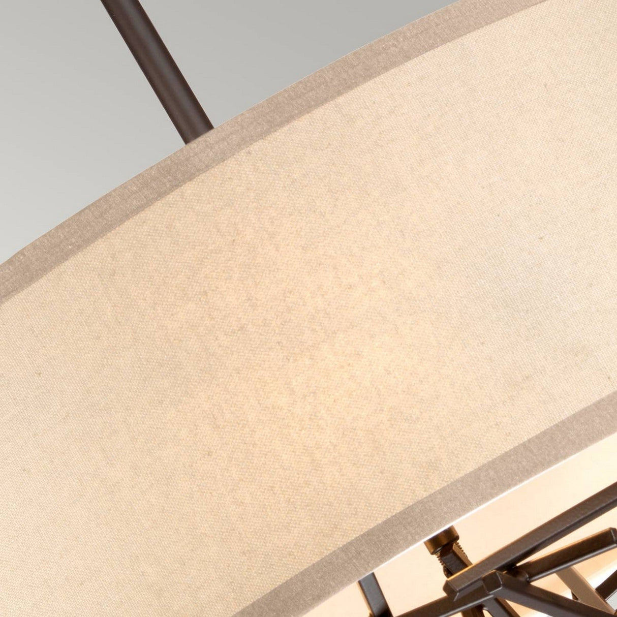 Close-up of the Taiko 3 Light Chandelier - Olde Bronze, showcasing a modern pendant with a circular beige fabric shade and an Olde Bronze metal frame. The light gently illuminates the space, emphasizing its sculptural texture and design.