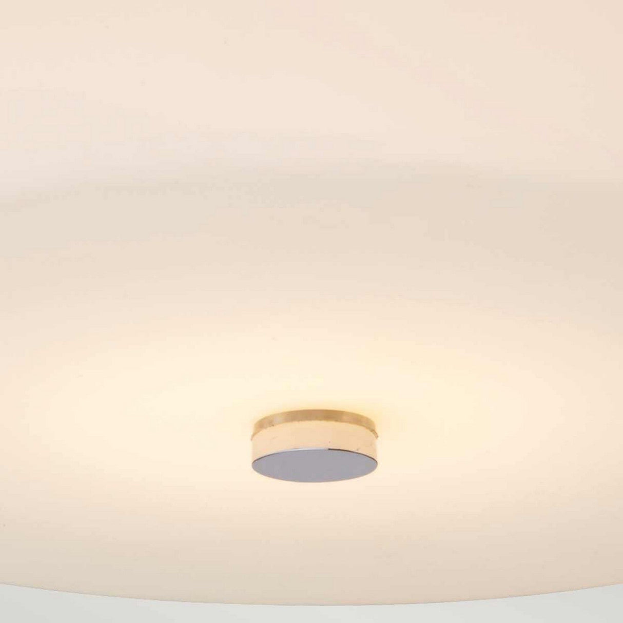 The Tamar 1 Light Medium Flush - Polished Chrome features a minimalistic ceiling light fixture with a circular design. It has an opal glass diffuser and an LED lamp that emits a warm glow to create an inviting atmosphere, blending seamlessly into the off-white ceiling.