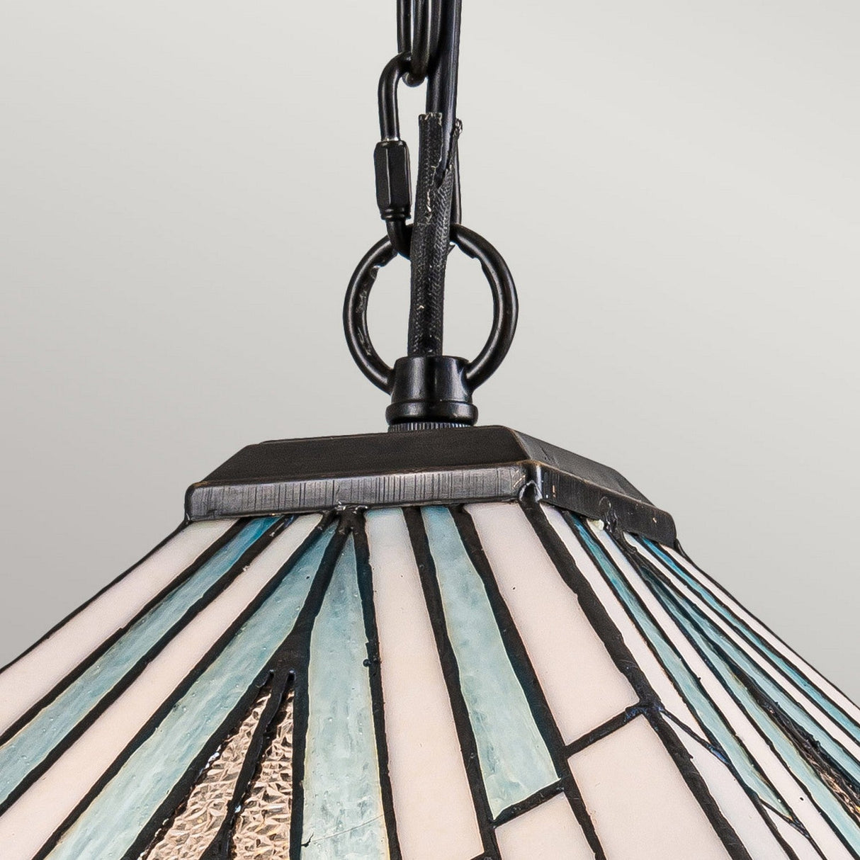 A close-up of the Alderley 2 Light Tiffany Pendant in Vintage Bronze, featuring stunning Art Deco styling with a geometric pattern in blue, white, and black. The lamp is elegantly suspended by a vintage bronze chain and frame, set against a plain light gray background.