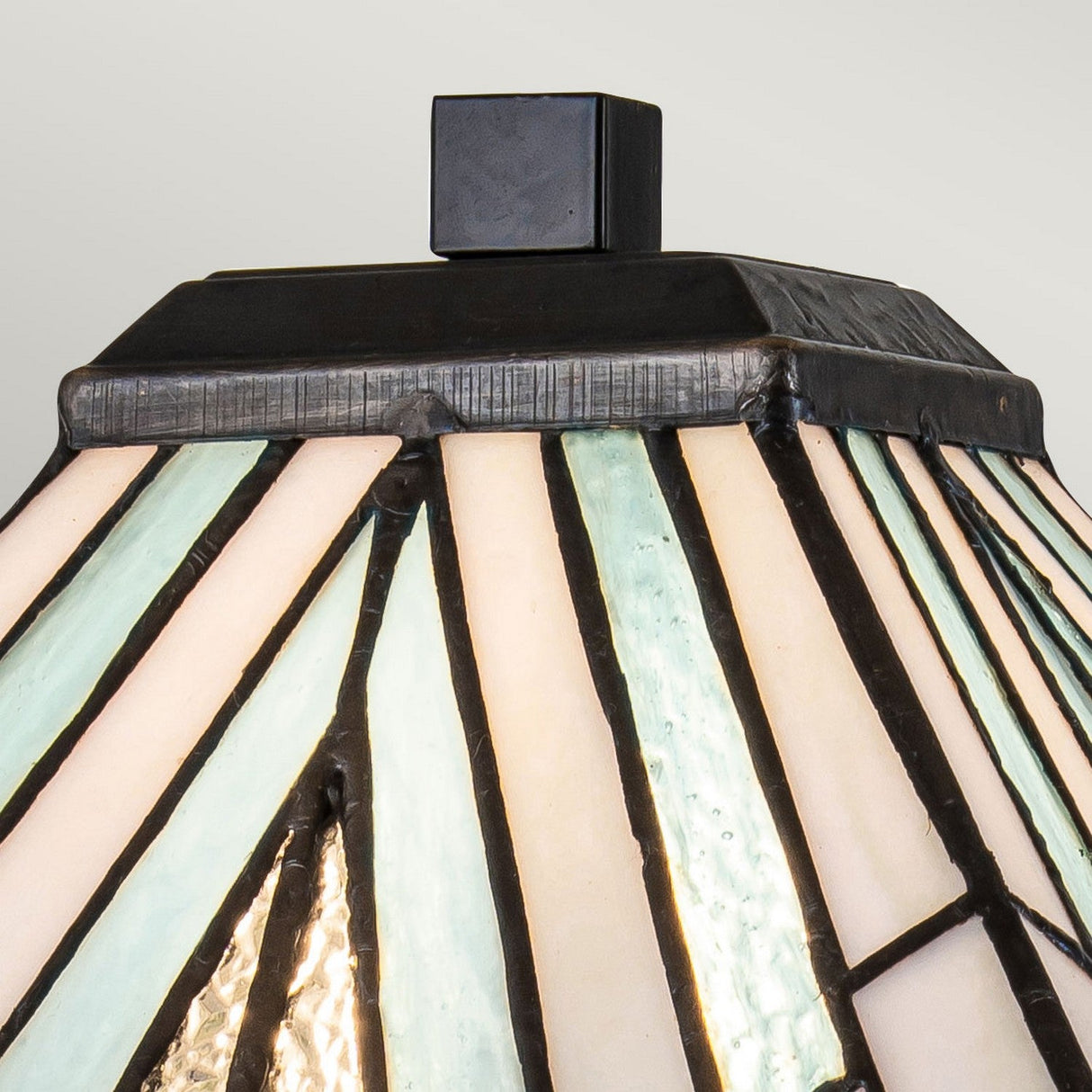 Close-up of an Alderley 1 Light Large Table Lamp in a Tiffany-style, showcasing a lampshade with a geometric design composed of cream and pale blue panels outlined by dark lines, topped with a sleek black square for an Art Deco finish.
