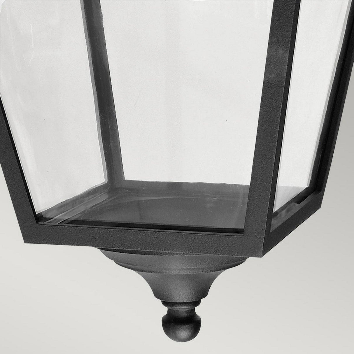 Close-up of the Turin Large Outdoor 1 Light Down Wall Lantern in Black, featuring a sleek geometric design with clear glass panels. The lantern is mounted upside down, highlighting its elegant finial detail and powder-coated finish. Its weather-resistant properties provide durability against the elements, all set against a simple background.