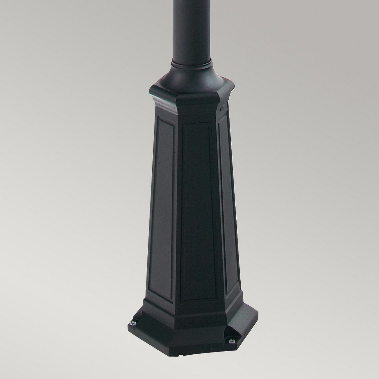 The image displays the base of the Turin Large 1 Light Single Post - Black street lamp, constructed from die-cast aluminium. Its hexagonal shape is embellished with decorative paneling, contributing to the elegance of this outdoor lighting fixture, set against a plain light grey backdrop.