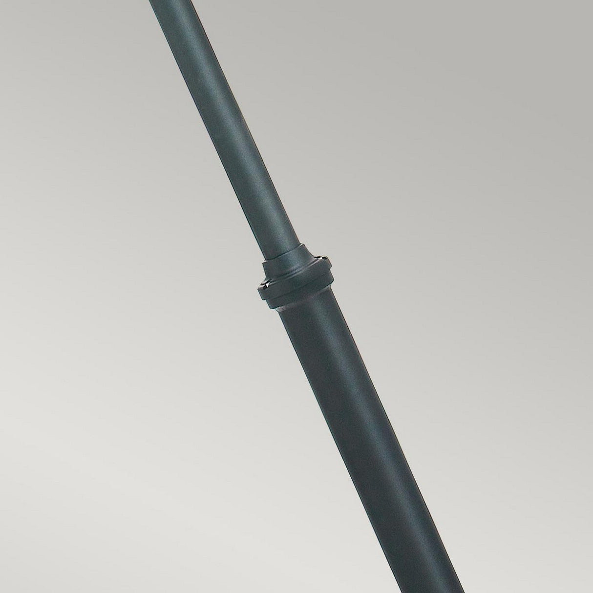 A close-up of the Turin Large 2 Light Twin Lamp Post in sleek black die-cast aluminum, showcasing its cylindrical form with a subtle bend. Positioned against a gray background, the lamp post features a central joint or clasp, hinting at its adjustable or extendable nature, which makes it perfect for outdoor lighting applications.