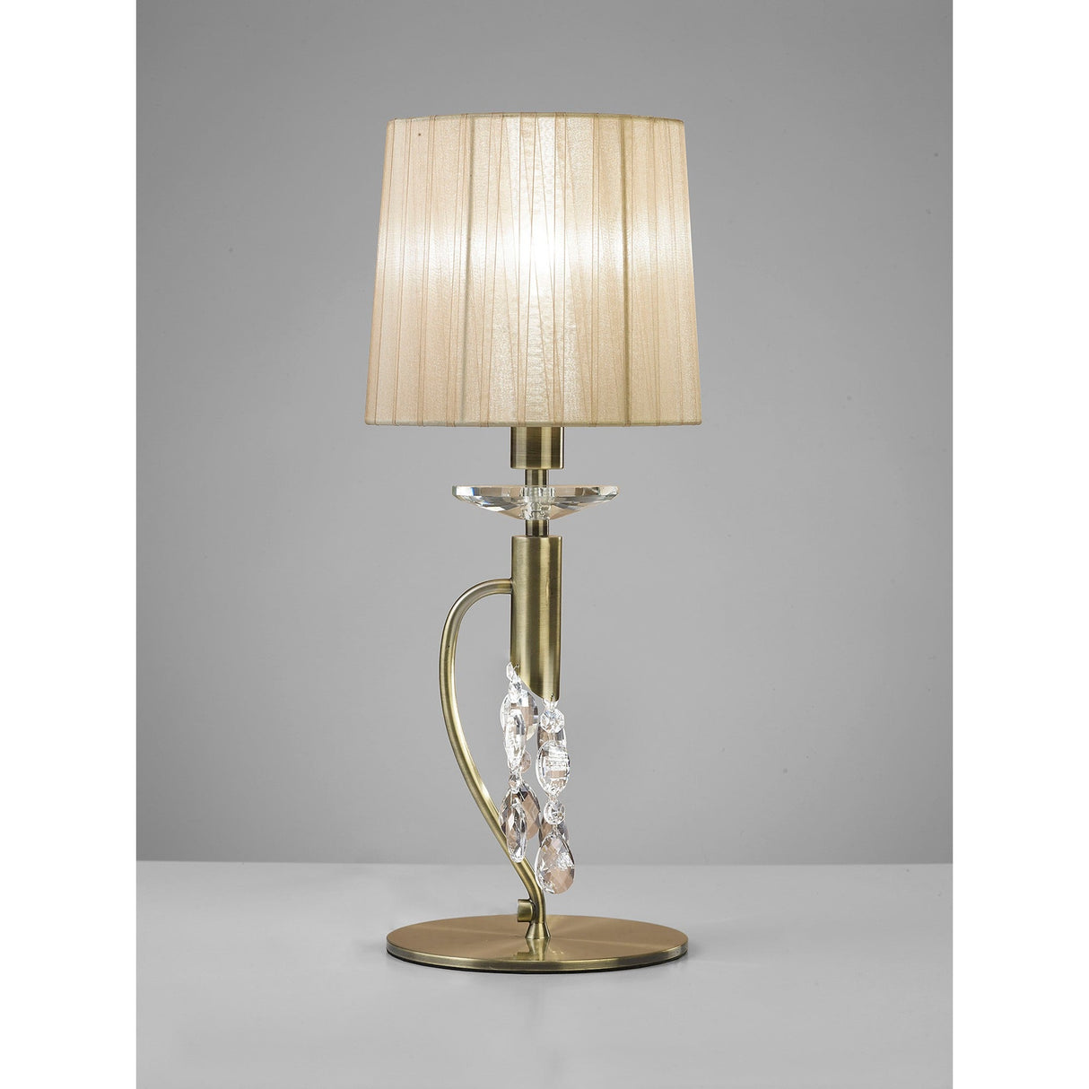 The Tiffany 2 Light Crystal Table Lamp features a brass finish, bronze shade, clear crystal accents on its curved stand, and a round base, all displayed on a white surface with a gray background.