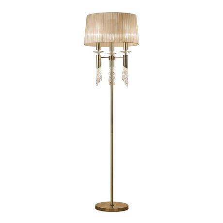 The Tiffany 6 Light Crystal Floor Lamp features a brass finish, bronze shade, round base, slender pole, and elegant hanging crystal accents. When lit, it emits a warm, inviting light perfect for any space.