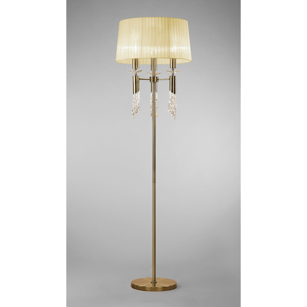The Tiffany 6 Light Crystal Floor Lamp features a brass finish, cream pleated shade, and elegant crystal accents for stylish lighting against a plain gray background.