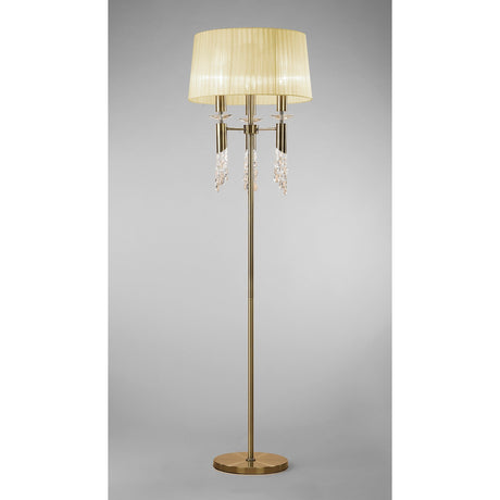 The Tiffany 6 Light Crystal Floor Lamp features a brass finish, cream pleated shade, and elegant crystal accents for stylish lighting against a plain gray background.
