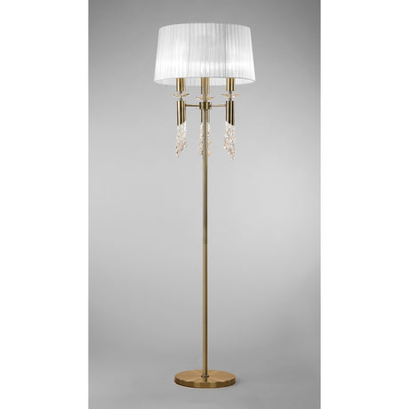 The Tiffany 6 Light Crystal Floor Lamp features a tall brass base, a round stand, white pleated shade, and sparkling crystal pendants below the shade, set against a plain gray background.