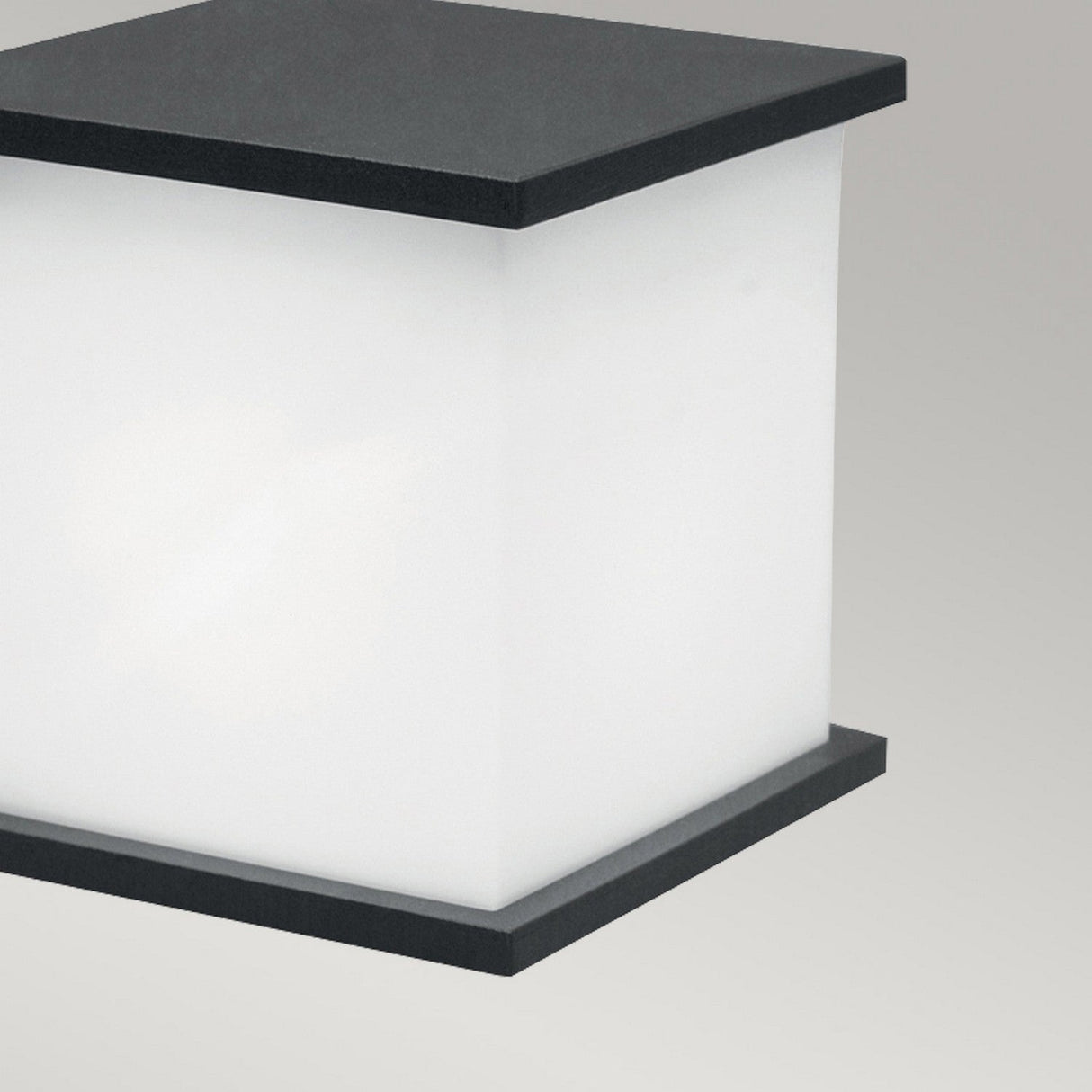 The Torsten 1 Light Outdoor Wall Fitting in graphite boasts a square shape with a matte black frame and frosted white glass panel, exuding modern minimalism while providing diffused illumination. Its weather-resistant design, reminiscent of an outdoor light, makes it versatile against a plain light gray background.