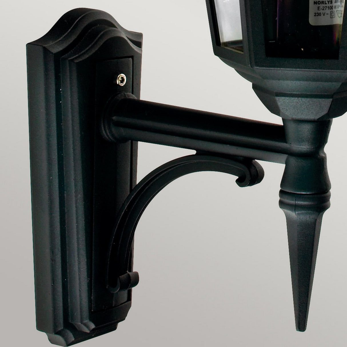 The Valencia Outdoor 1 Light Up Lantern in black, crafted from die-cast aluminum, boasts a weather-resistant finish. Its elegant structure features a rectangular base and curved arm, standing gracefully against a plain gray background with a classic design that includes a pointed detail at the bottom.