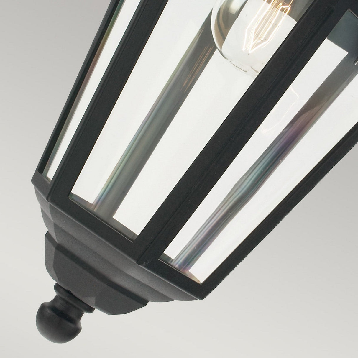 Close-up of the Valencia Outdoor 1 Light Chain Pendant in black, featuring a design crafted from die-cast aluminum with geometric lines and clear glass panels that reveal an exposed bulb. The backdrop is a simple gray gradient, enhancing this elegant piece of outdoor lighting.