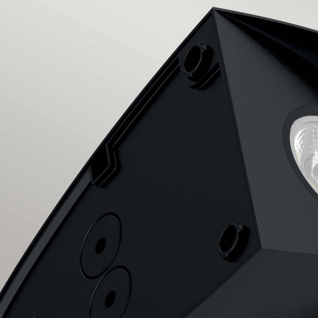 Close-up of the Vendela Outdoor LED Wall Light in black, highlighting its circular ports and a clear component that suggests energy-efficient illumination. The background is a plain, light gray color, subtly mirroring the sleek design characteristic of this IP65-rated durable device.