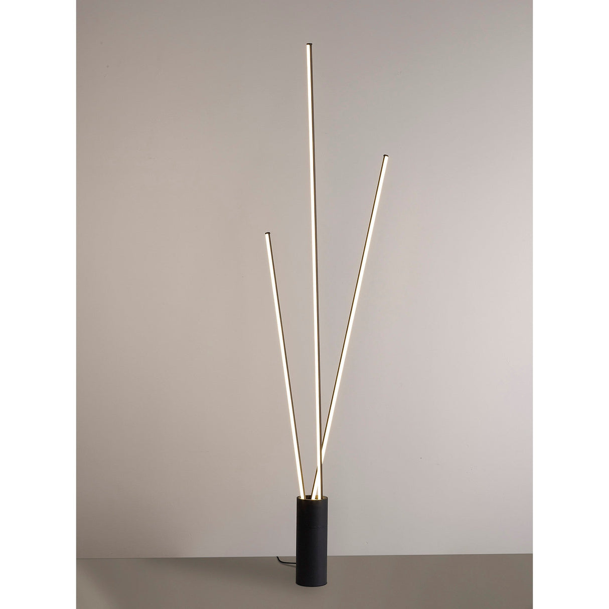 The Vertical Dimmable LED Floor Lamp 60W 3000K in black features three slim, vertical rods of different heights rising from a cylindrical base, providing energy-efficient lighting and a sleek modern look.