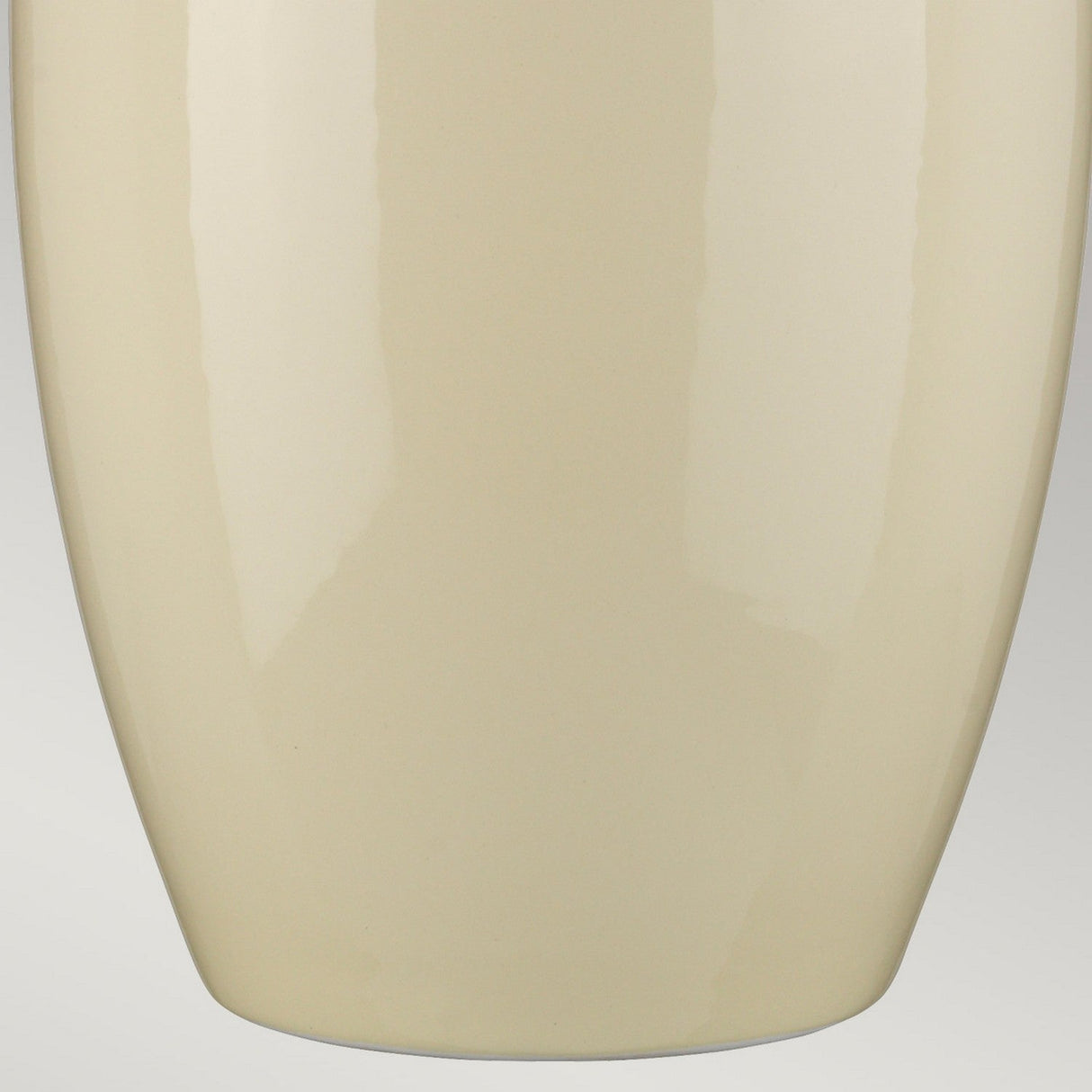 A close-up of the Victor 1 Light Large Table Lamp in Cream showcases its smooth, light beige ceramic base with a glossy finish, reminiscent of an elegant vase. The lamp's surface reflects light, highlighting its clean and modern design while the gray background accentuates its elegant simplicity, similar to the effect created by a faux silk shade.